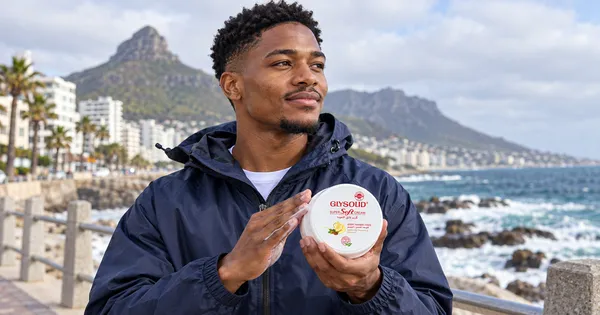 A young man on the windy Sea Point promenade rubbing Glysolid Super Soft Cream into his hands.